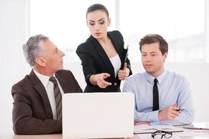 Working on project together. Three confident business people discussing something while looking at the laptop photo