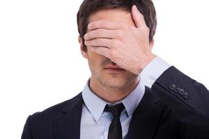 I saw nothing. Portrait of young man in formalwear covering eyes with hand while standing isolated on white background photo