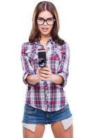 Action Beautiful young woman holding movie camera while standing against white background photo