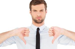 Rejected Portrait of confident young man in shirt and tie looking at camera and showing his thumbs down while standing isolated on white background photo