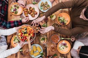 Friends having dinner. Top view of four people having dinner together while sitting at the rustic wooden table photo