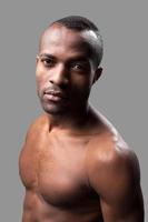 Manly and muscular. Shirtless African man looking at camera while standing against grey background photo