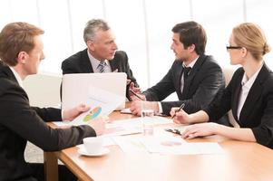 Hot discussion. Four business people in formalwear discussing something while sitting together at the meeting photo