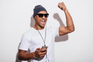 I love this track Happy young African man in headphones holding his music player and gesturing while standing against white background photo