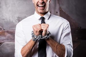 Begging for freedom. Close-up of furious young businessman grimacing while being trapped in chains photo