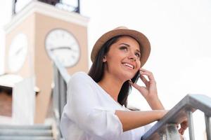 Good talk with friend. Low angle view of beautiful young woman in funky hat looking away and smiling while standing outdoors photo