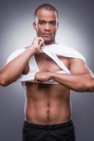 Too sexy for his shirt. Handsome young African man taking off his tank top and looking at camera while standing against grey background photo