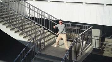 elegante caucasico uomo nel occhiali da sole strada ballerino danza rompere danza su il sfondo di il urbano architettura. il giovane tipo è l'esecuzione stile libero. lento movimento. video