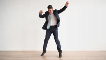 Funny business man dancing for joy and success on a white background. Happy office worker in formal clothes laughs and jumps with victory happiness. Emotions of a winner, career growth.