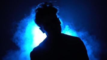 silhouette, uomo strada ballerino danza elegante danza nel un' fumoso camera con sostegno blu neon luce. video