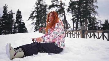 una chica feliz y hermosa con equipo de esquí jugada en la nieve y sonríe a la cámara con el telón de fondo de montañas nevadas y bosques. concepto de viajes y vacaciones. camara lenta. video