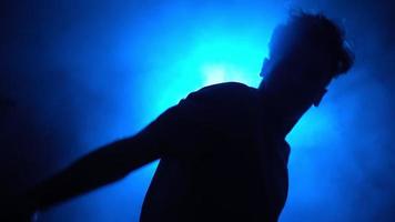 Silhouette, man street dancer dancing stylish dance in a smoky room with backing blue neon light. video