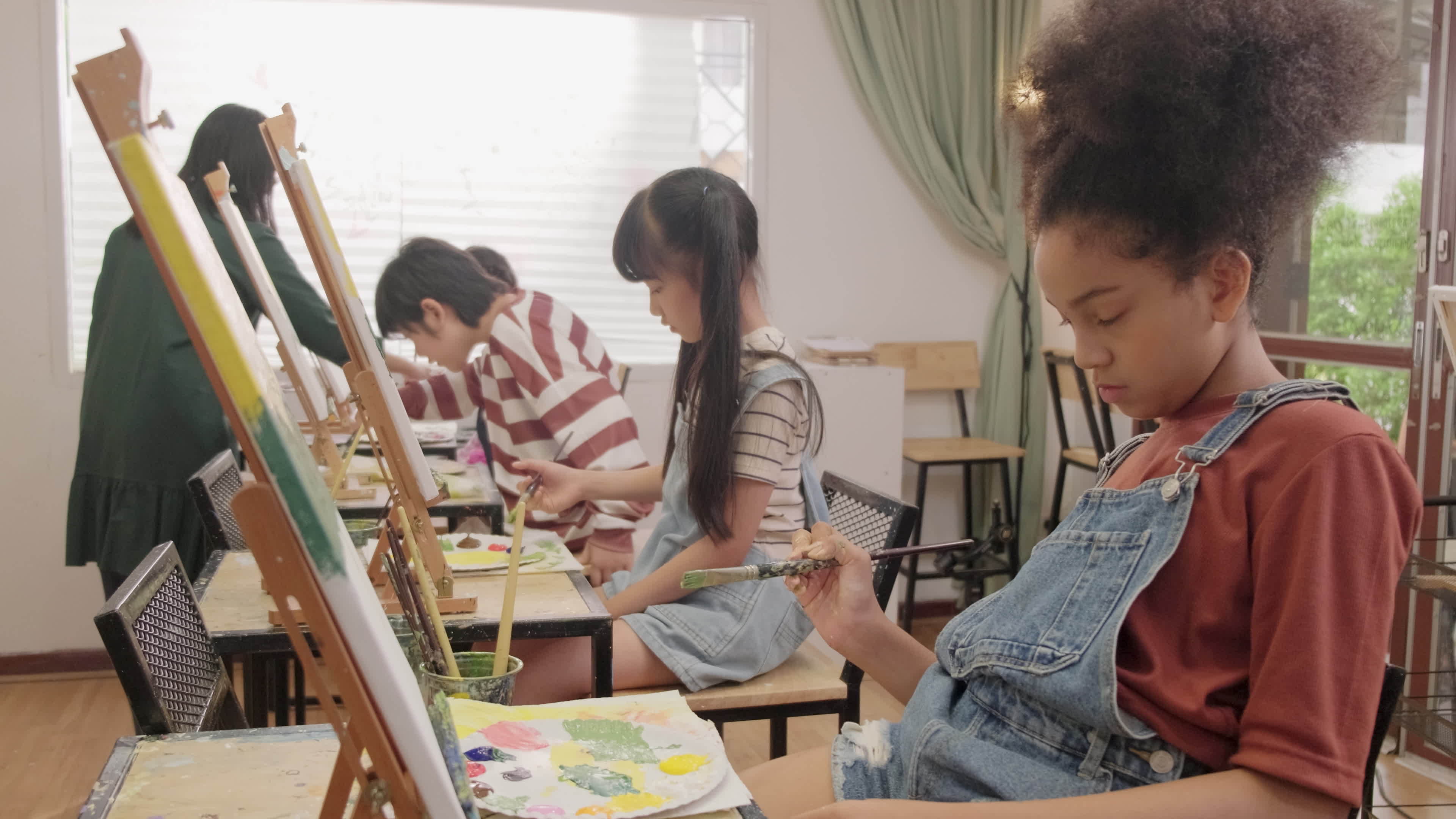 A group of multiracial kids learning with a female Asian teaches