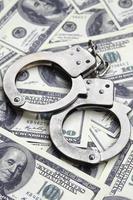 Police handcuffs lie on a lot of dollar bills. The concept of illegal possession of money, illegal transactions with US dollars. Economic Crime photo