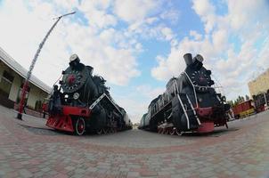 Photo of old black steam locomotives of the Soviet Union. Strong distortion from the fisheye lens