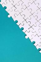 Fragment of a folded white jigsaw puzzle on the background of a blue plastic surface. Texture photo with copy space for text