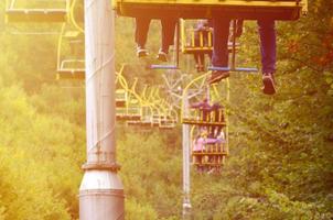 la gente viaja en un teleférico. las piernas de los pasajeros cuelgan sobre el bosque de montaña foto