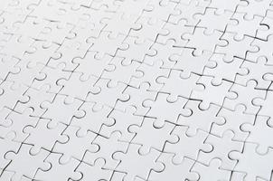 Close up of a white jigsaw puzzle in assembled state in perspective. Many components of a large whole mosaic are united photo