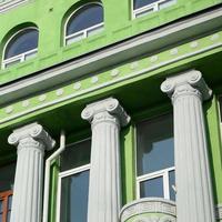 Restored old multi-storey building with antique columns, painted in green photo