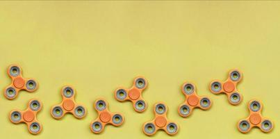 Many orange fidget spinners lies on texture background of fashion pastel orange color paper photo