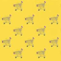 Shopping addiction, shopping lover or shopaholic concept. Many small empty shopping carts perform a pattern on a pastel colored paper background. Flat lay composition, top view photo