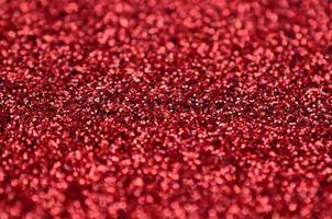una gran cantidad de lentejuelas decorativas rojas. textura de fondo con elementos pequeños y brillantes que reflejan la luz en un orden aleatorio. textura brillo foto