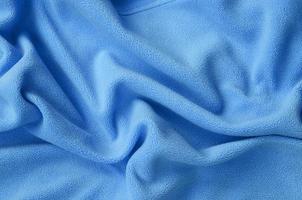 The blanket of furry blue fleece fabric. A background of light blue soft plush fleece material with a lot of relief folds photo