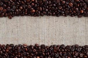 Texture of a gray canvas made of old and coarse burlap with coffee beans on it photo