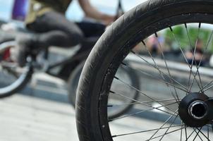 A BMX bike wheel against the backdrop of a blurred street with cycling riders. Extreme Sports Concept photo