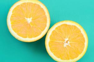Top view of a several orange fruit slices on bright background in turquoise green color. A saturated citrus texture image photo