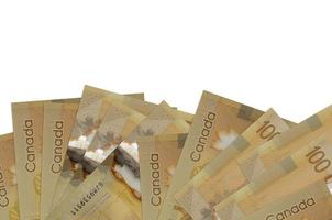 Los billetes de 100 dólares canadienses se encuentran en la parte inferior de la pantalla aislados en fondo blanco con espacio de copia. plantilla de banner de fondo foto