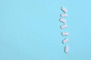 A few chewing gums lie on texture background of fashion pastel blue color paper in minimal concept photo