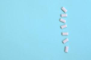 A few chewing gums lie on texture background of fashion pastel blue color paper in minimal concept photo