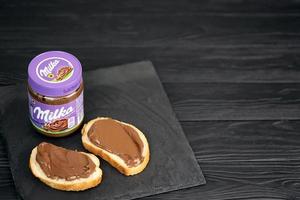 KHARKOV, UKRAINE - JULY 2, 2021 Can of Milka sweetened hazelnut cocoa spread with classical lilac color design on black table photo