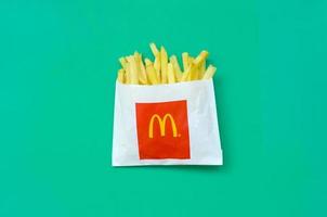 kharkov, ucrania - 9 de diciembre de 2020 papas fritas de mcdonald's en una pequeña bolsa de papel sobre fondo verde brillante foto