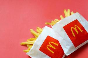 kharkov, ucrania - 9 de diciembre de 2020 papas fritas de mcdonald's en una pequeña bolsa de papel sobre fondo rojo brillante foto