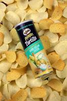 KHARKOV. UKRAINE - MAY 2, 2019 Pringles sour cream fiesta flavour. Cardboard tube can on many Pringles potato chips background. Pringles is a brand of snack chips owned by Kellogg Company photo