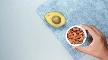 Avocado half with and cup of almonds on table for a snack video