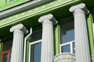 Restored old multi-storey building with antique columns, painted in green photo