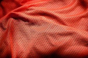 Red sport clothing fabric texture background. Top view of red cloth textile surface. Bright basketball shirt. Text Space photo