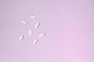 A few chewing gums lie on texture background of fashion pastel pink color paper