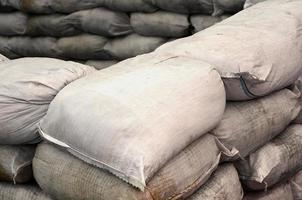 fondo de muchas bolsas de arena sucias para la defensa contra inundaciones. barricada protectora de sacos de arena para uso militar. hermoso búnker táctico foto