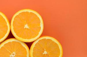 Top view of a several orange fruit slices on bright background in orange color. A saturated citrus texture image photo