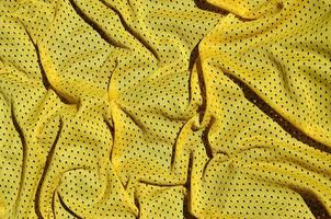 Sport clothing fabric texture background. Top view of yellow polyester nylon cloth textile surface. Colored basketball shirt with free space for text photo