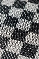 Plastic texture in the form of a very small cloth binding, painted in black and gray in the style of a chessboard. Macro shot photo