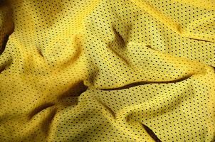 Sport clothing fabric texture background. Top view of yellow polyester nylon cloth textile surface. Colored basketball shirt with free space for text photo