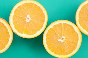 Top view of a several orange fruit slices on bright background in turquoise green color. A saturated citrus texture image photo