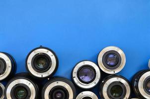 Several photographic lenses lie on a bright blue background. Space for text photo