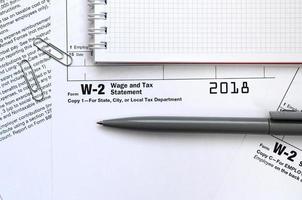 el bolígrafo y el cuaderno en el formulario de impuestos w-2 declaración de salarios e impuestos. la hora de pagar impuestos foto