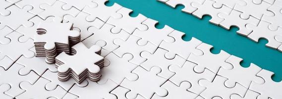The blue path is laid on the platform of a white folded jigsaw puzzle. The missing elements of the puzzle are stacked nearby. Texture image with space for text photo